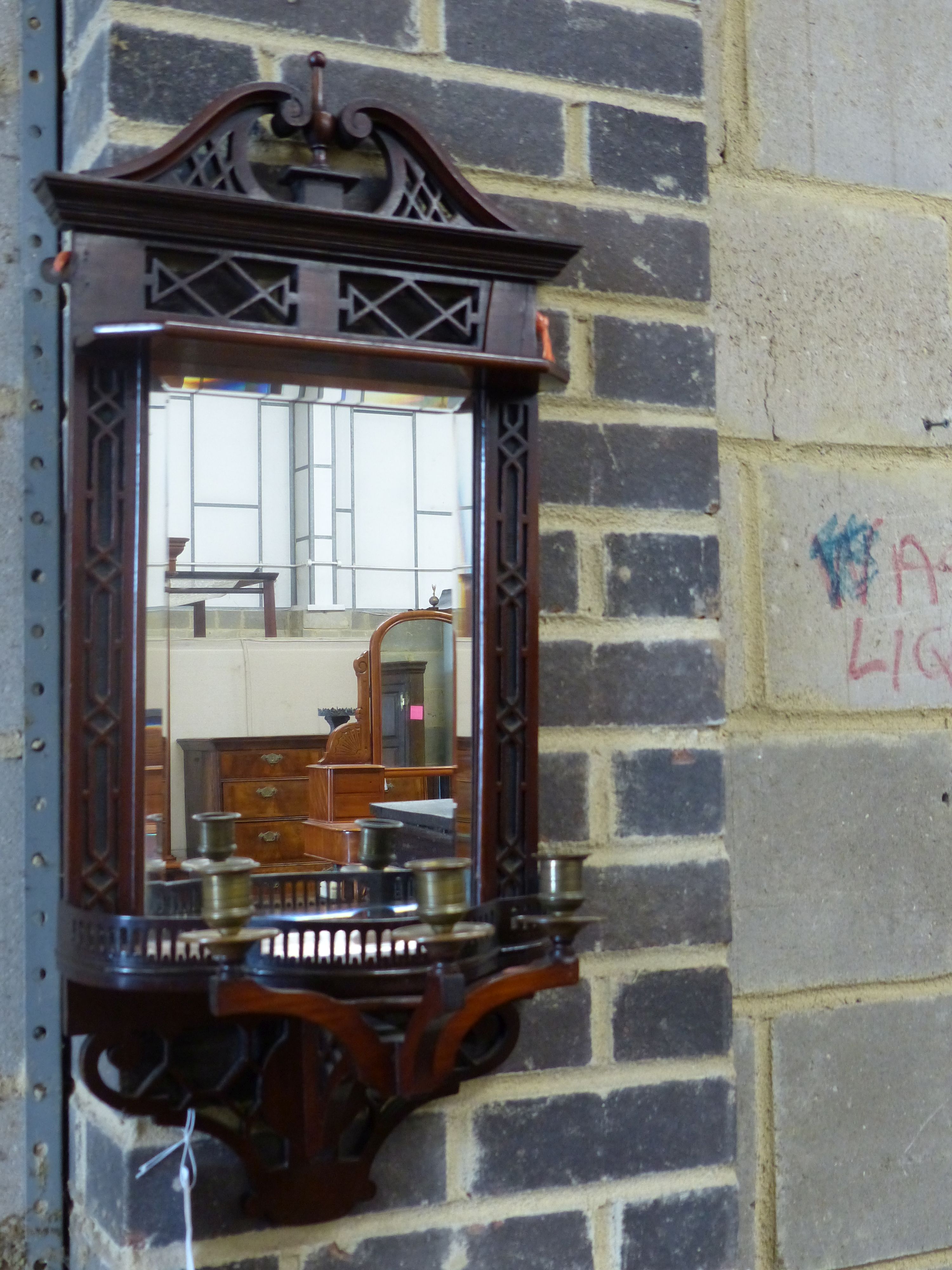 An Edwardian mahogany mirrored wall bracket with triple brass sconce, width 31cm height 75cm